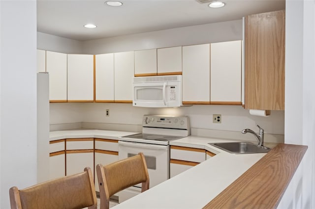 kitchen with recessed lighting, white appliances, light countertops, and a sink