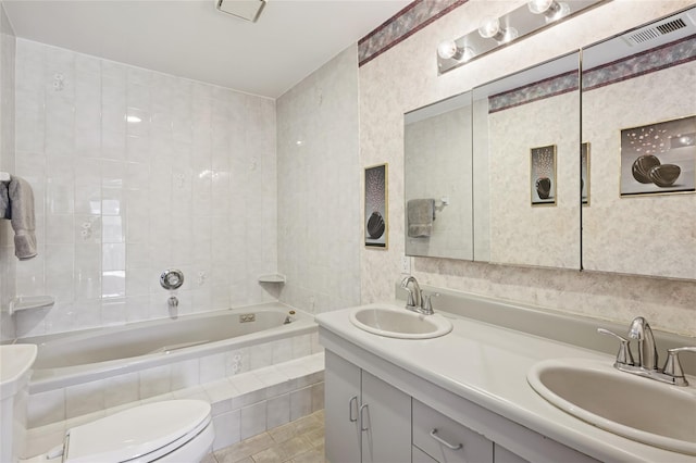 bathroom featuring a sink, toilet, double vanity, and tiled bath