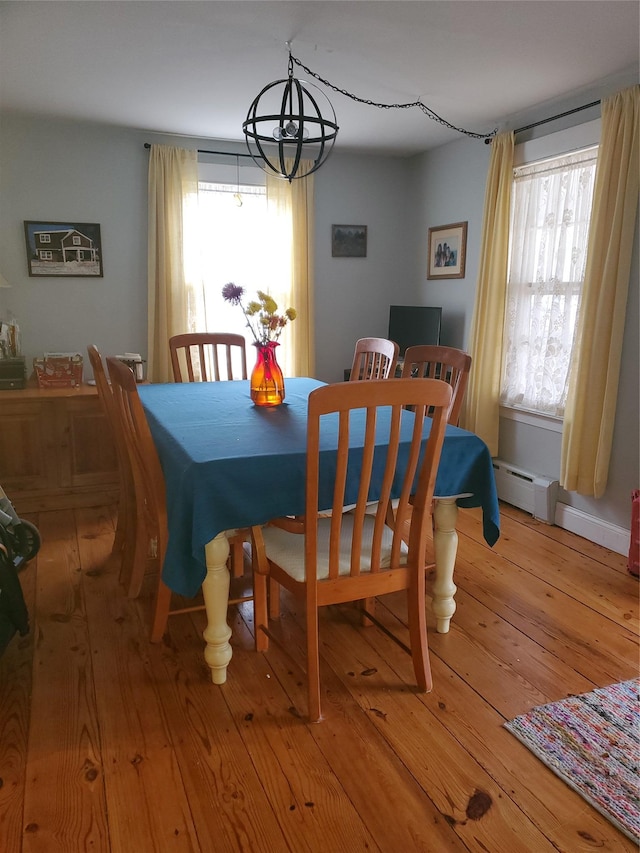 dining space featuring baseboard heating, light wood-style flooring, and a healthy amount of sunlight