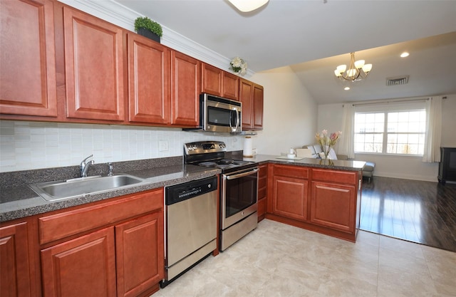 kitchen with a peninsula, a sink, visible vents, appliances with stainless steel finishes, and dark countertops