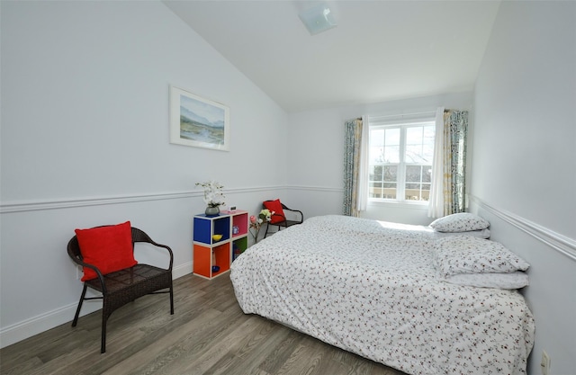 bedroom featuring baseboards, vaulted ceiling, and wood finished floors