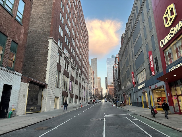 view of street with sidewalks, street lighting, a view of city, and curbs