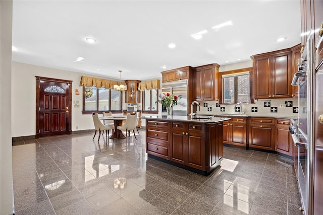 kitchen featuring built in fridge, recessed lighting, granite finish floor, a sink, and baseboards