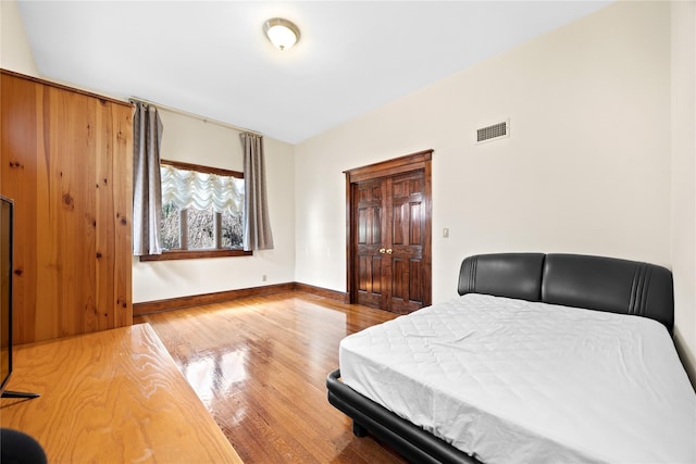 bedroom with a closet, wood finished floors, visible vents, and baseboards