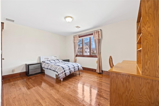 bedroom featuring wood finished floors, visible vents, and baseboards