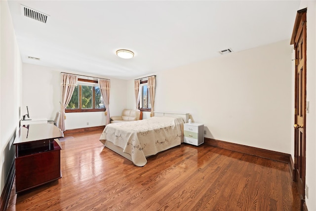 bedroom with wood finished floors, visible vents, and baseboards