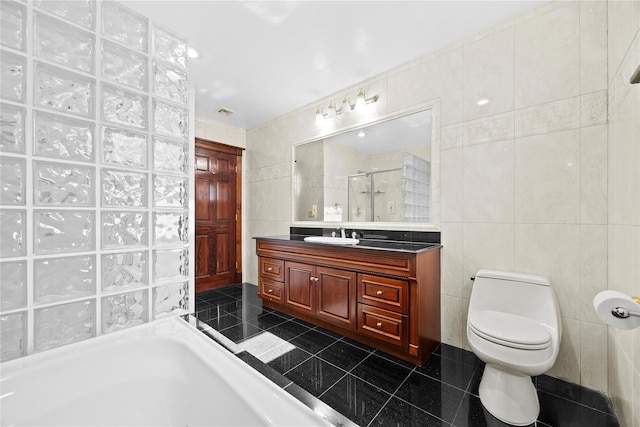 full bath with a stall shower, toilet, tile patterned flooring, vanity, and tile walls