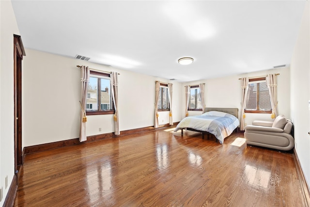 bedroom with visible vents, multiple windows, and wood finished floors