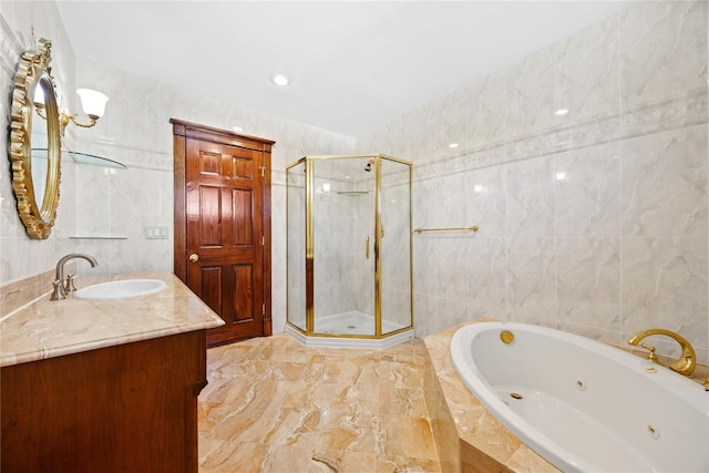 bathroom with a jetted tub, vanity, tile walls, and a stall shower