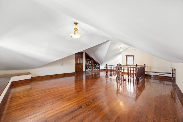 bonus room featuring lofted ceiling, a baseboard heating unit, baseboards, and wood finished floors