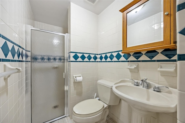 bathroom with a stall shower, a sink, toilet, and tile walls