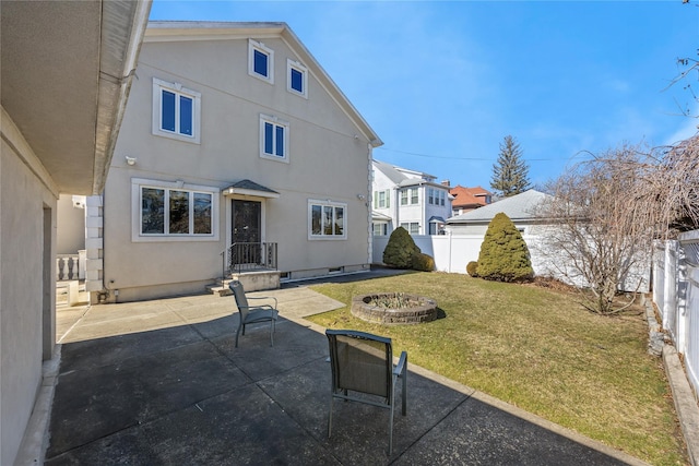 rear view of house with a patio, an outdoor fire pit, a fenced backyard, and stucco siding