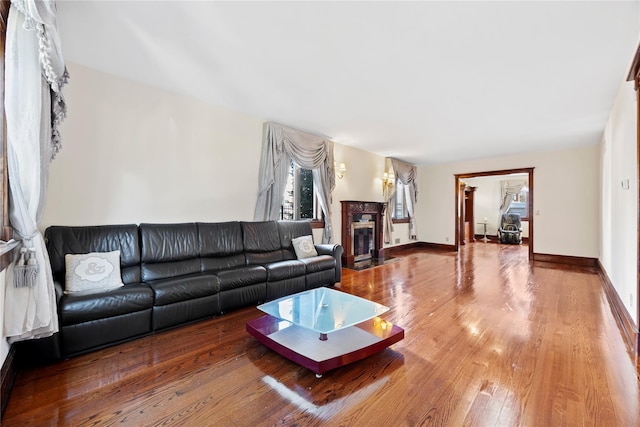 living room with wood-type flooring, a fireplace with flush hearth, and baseboards