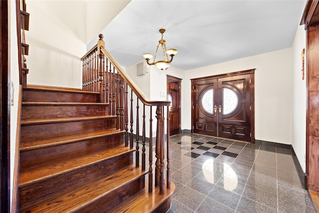 foyer entrance with a chandelier, granite finish floor, baseboards, and stairs