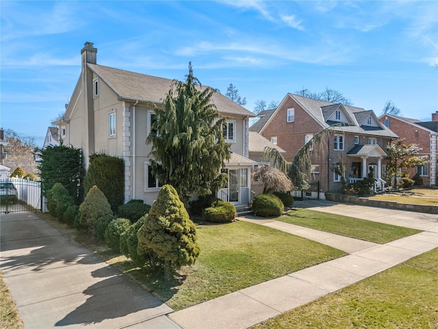 view of front of property featuring a chimney, stucco siding, fence, a residential view, and a front lawn