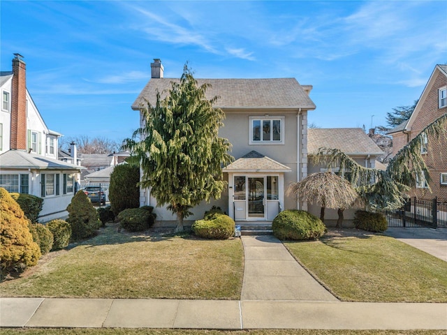 view of front of house featuring a chimney, stucco siding, a shingled roof, fence, and a front lawn