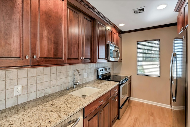 kitchen with visible vents, crown molding, baseboards, stainless steel appliances, and a sink