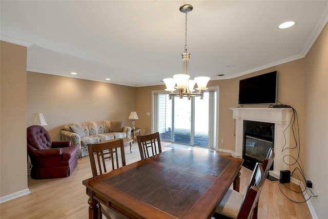 dining room featuring a premium fireplace, baseboards, ornamental molding, and light wood finished floors