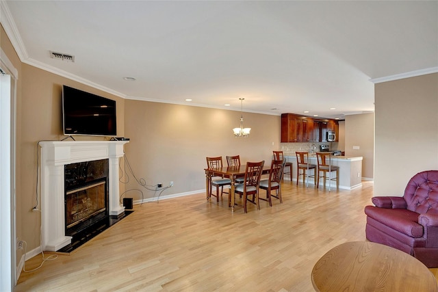 dining room featuring crown molding, light wood-style floors, and visible vents