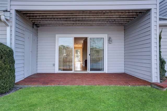 doorway to property with a patio and a lawn