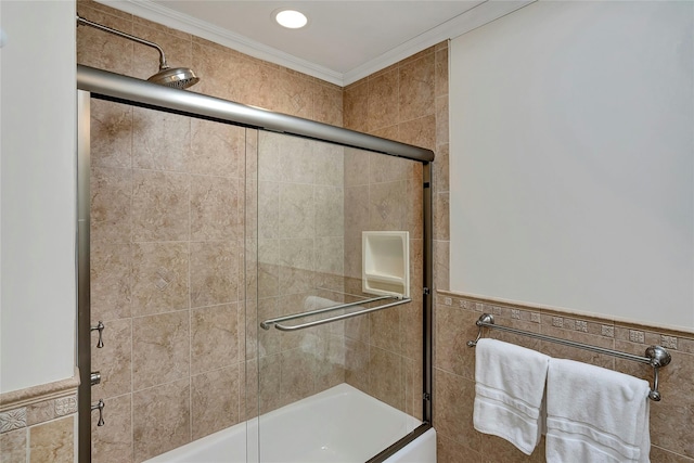 full bath with tile walls, crown molding, and combined bath / shower with glass door