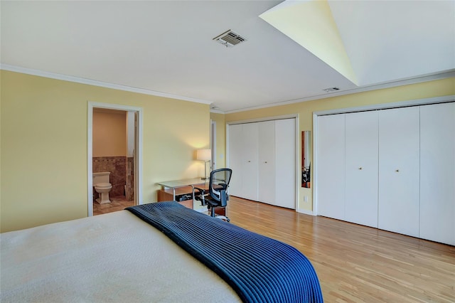 bedroom with visible vents, crown molding, light wood-style floors, and multiple closets