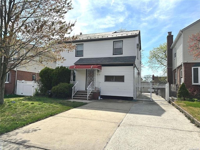 view of front facade with driveway, a front yard, fence, and a gate