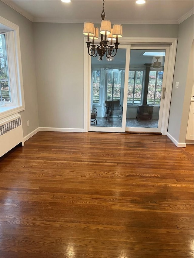 unfurnished dining area with baseboards, radiator, dark wood-style floors, crown molding, and a notable chandelier