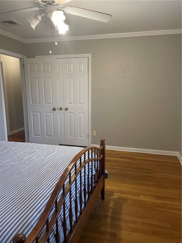 bedroom with baseboards, visible vents, wood finished floors, and ornamental molding