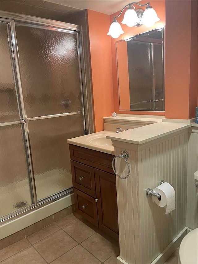 bathroom featuring tile patterned flooring, a shower stall, toilet, and vanity