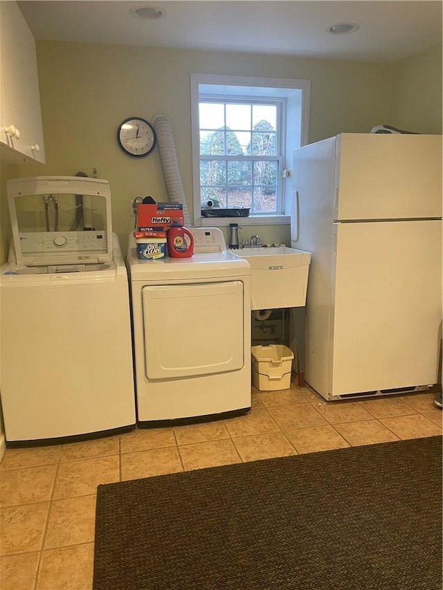 laundry room featuring cabinet space, light tile patterned floors, a sink, and washing machine and clothes dryer