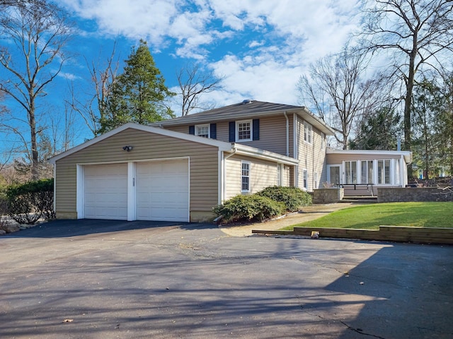 view of front of property with a front yard, an attached garage, and driveway