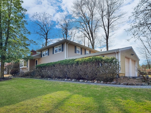 view of side of home with a lawn, an attached garage, and a chimney