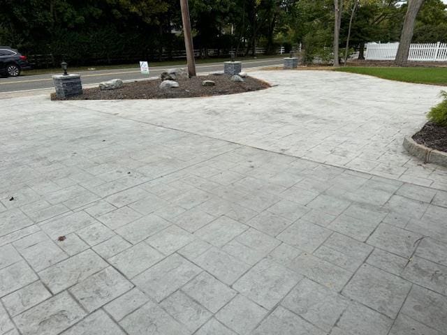 exterior space featuring decorative driveway and fence