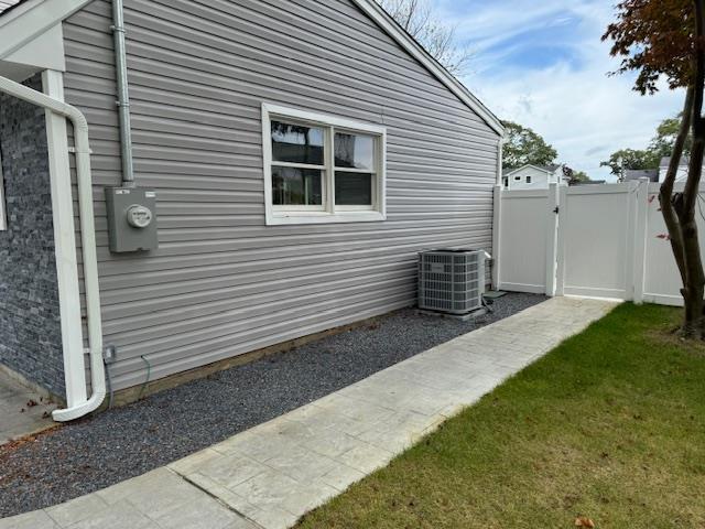 view of property exterior with cooling unit, a gate, and fence