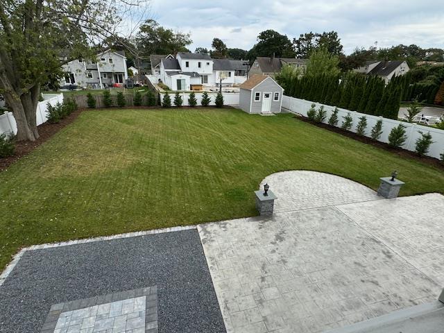 view of yard featuring a storage shed, an outdoor structure, a fenced backyard, and a residential view