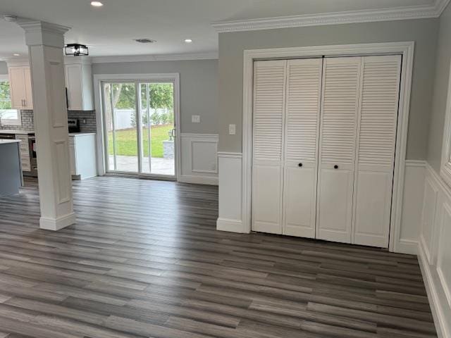 interior space featuring ornamental molding, a wainscoted wall, a healthy amount of sunlight, and dark wood-type flooring