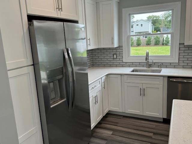 kitchen with a sink, white cabinetry, light countertops, appliances with stainless steel finishes, and dark wood-style floors