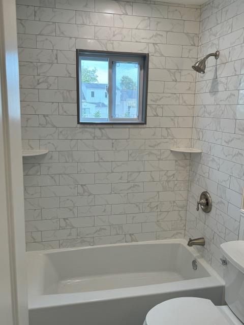 bathroom with toilet and bathing tub / shower combination