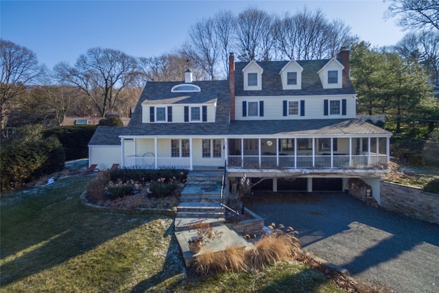 view of front of home featuring a chimney, a carport, asphalt driveway, and a sunroom