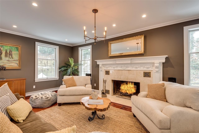 living area featuring a baseboard radiator, a tiled fireplace, a chandelier, recessed lighting, and crown molding