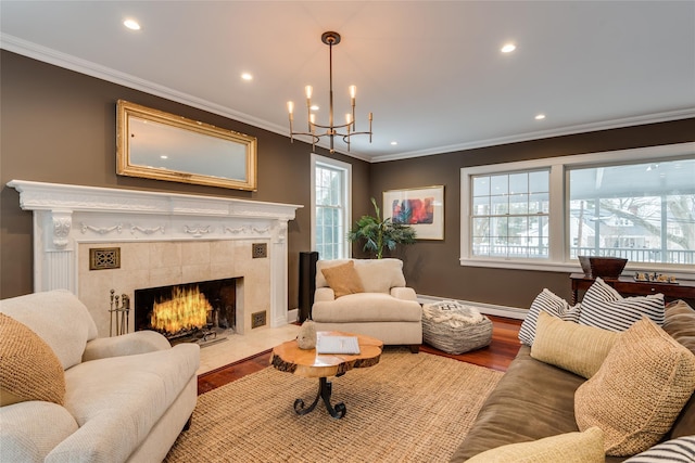 living room with a fireplace, wood finished floors, crown molding, a chandelier, and healthy amount of natural light