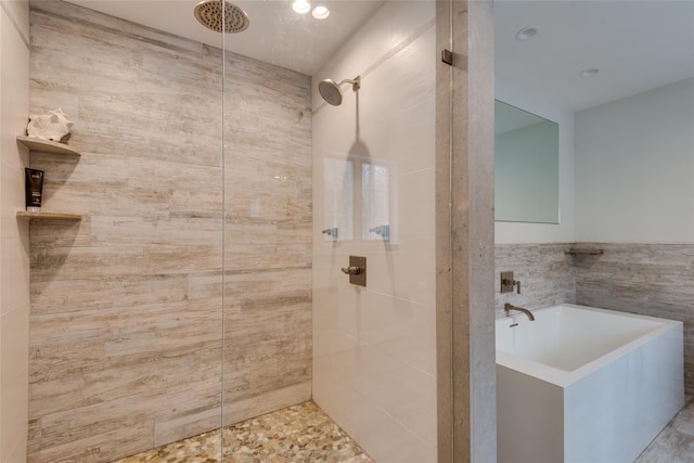 full bathroom featuring tiled shower, tile walls, and a bath