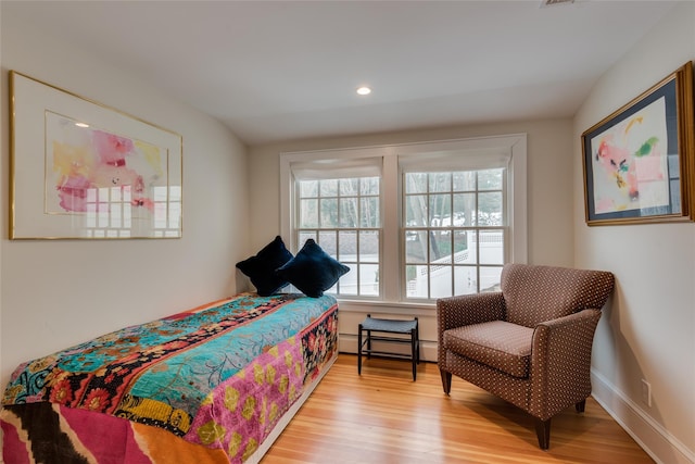bedroom with multiple windows, a baseboard heating unit, light wood-style floors, and recessed lighting