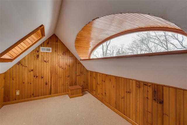 additional living space featuring wooden walls, lofted ceiling, and carpet flooring