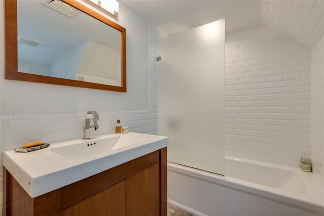 full bath featuring bathtub / shower combination, vanity, backsplash, and vaulted ceiling