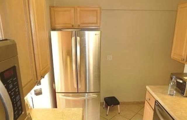 kitchen featuring baseboards, appliances with stainless steel finishes, light countertops, light brown cabinets, and light tile patterned flooring