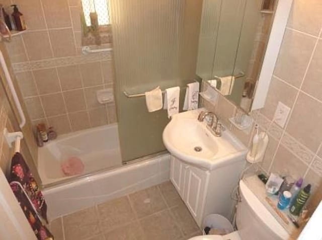 full bathroom with tile walls, shower / bath combination, toilet, vanity, and tile patterned floors