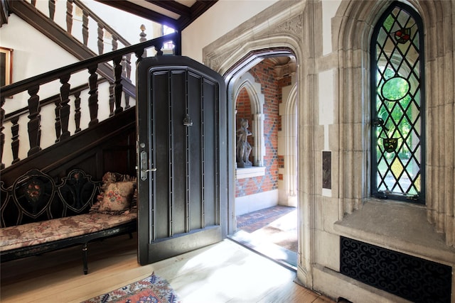 entrance foyer with brick wall, stairs, and wood finished floors