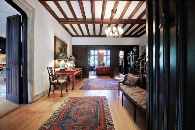 entryway with a chandelier, french doors, lofted ceiling with beams, and light wood-type flooring